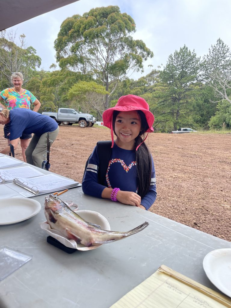 A girl weighs a fish she just caught