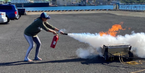Staff practice putting out a fire with an extinguisher.
