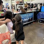 A father holds his daughter steady as she tackles her first virtual fish
