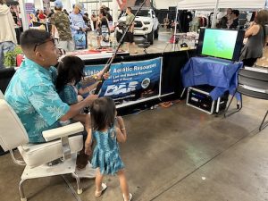 A father guides his daughters to landing their first fish