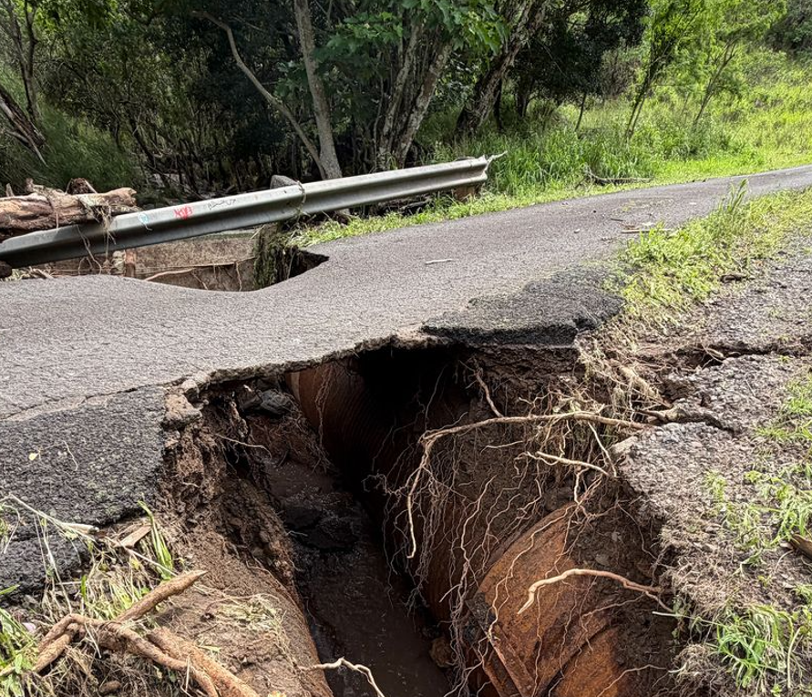 close up of erosion damage to roadway exposing a large gap and deteriorating asphalt.