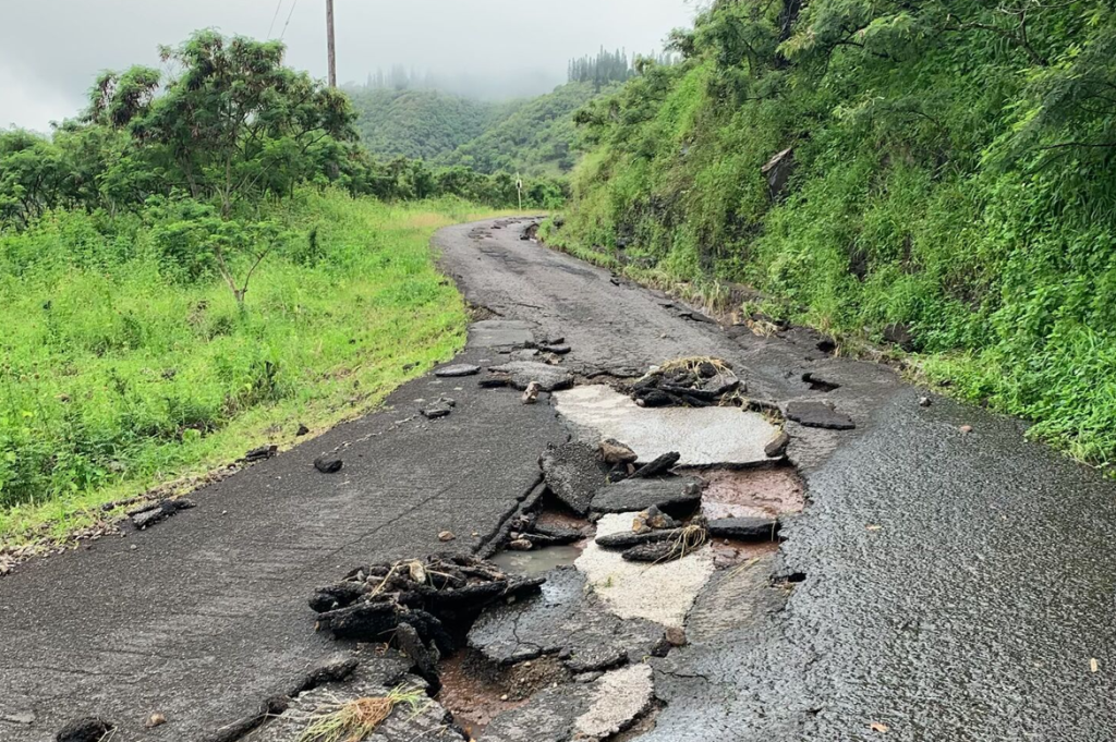 S-curved roadway shows chunks of asphalt and large gouges out of the street's center.